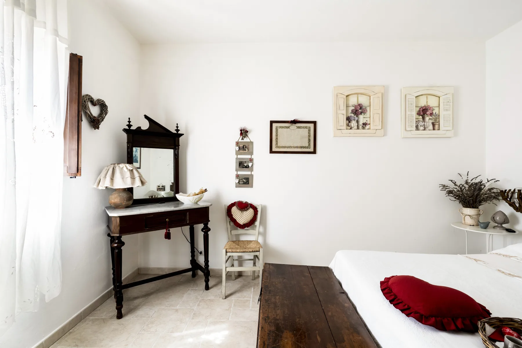 Un dormitorio luminoso con una cama de madera oscura y un pequeño tocador.