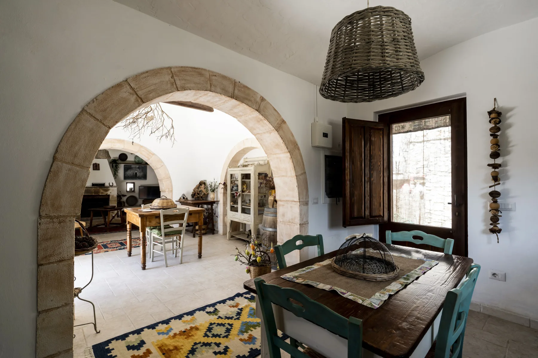 Un comedor con una mesa de madera está junto a un arco de piedra que conduce a otra habitación.