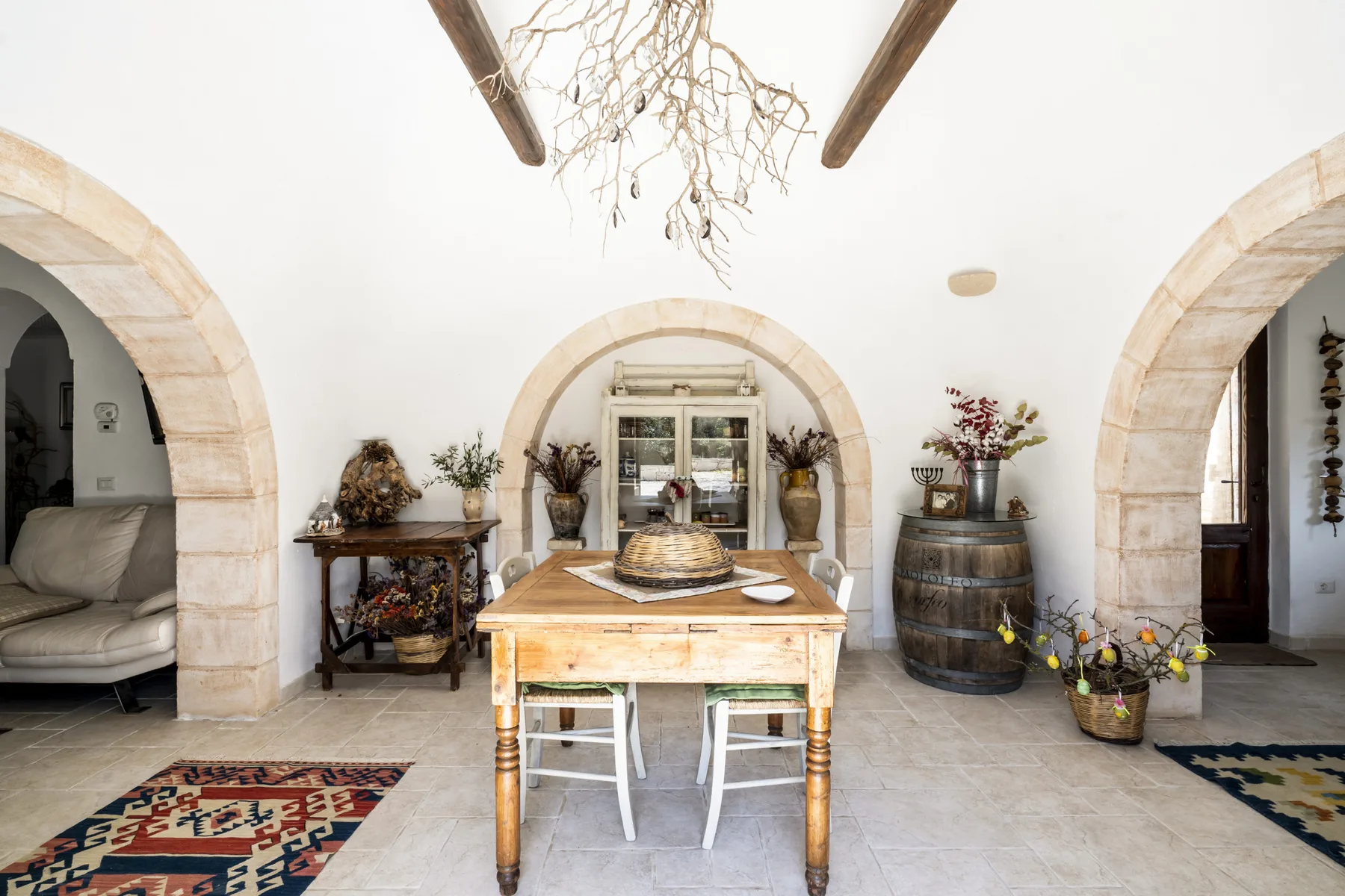 Un comedor luminoso cuenta con una mesa de madera bajo arcos de piedra.