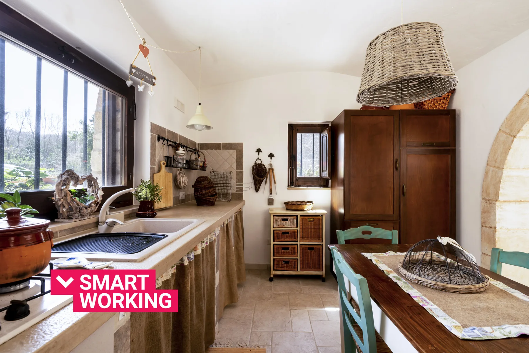 Una cocina rústica con una encimera larga, fregadero y mesa de comedor de madera.