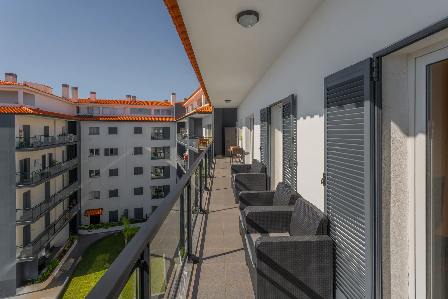Un pasillo de balcón con asientos al aire libre da a edificios de apartamentos cercanos.