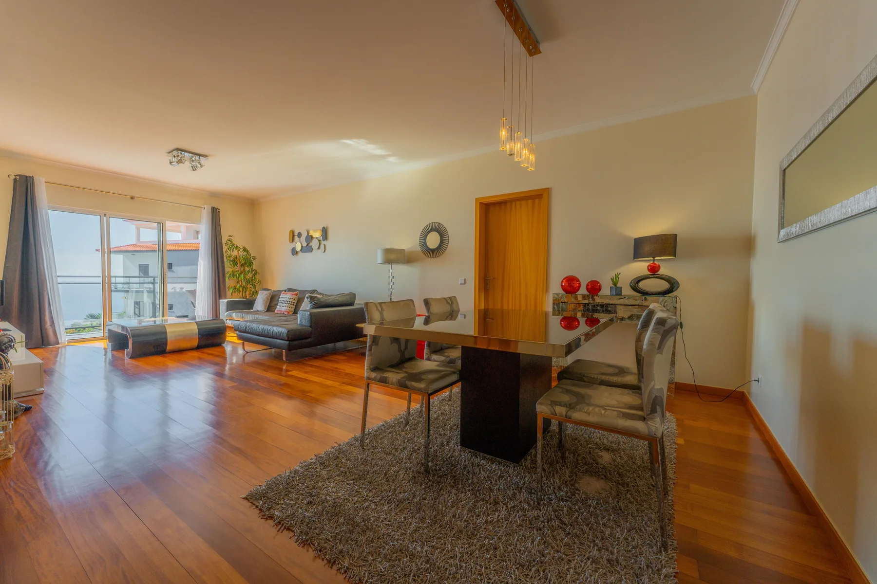 Salón y comedor con asientos, mesa de comedor y puertas al balcón.