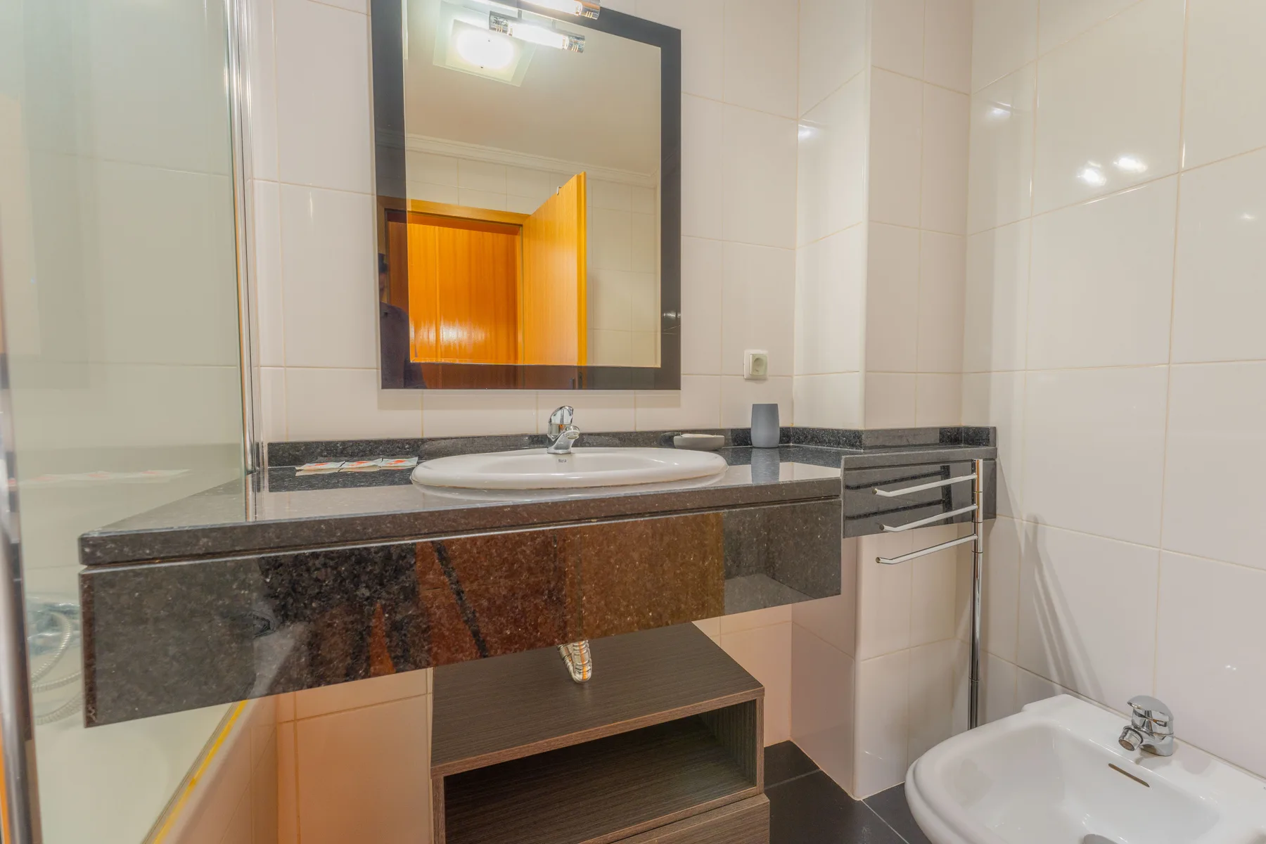 Un baño alicatado con lavabo, espejo y bidé.