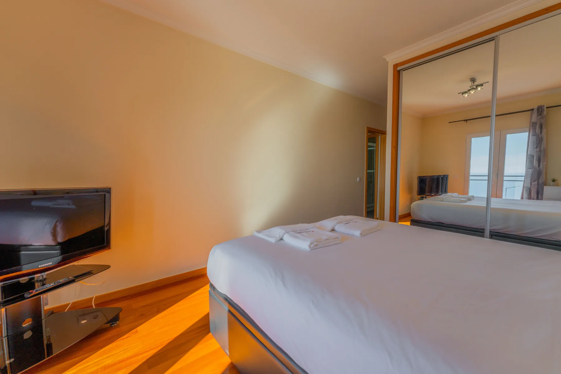 Un dormitorio con una cama tendida y un televisor sobre un mueble bajo.