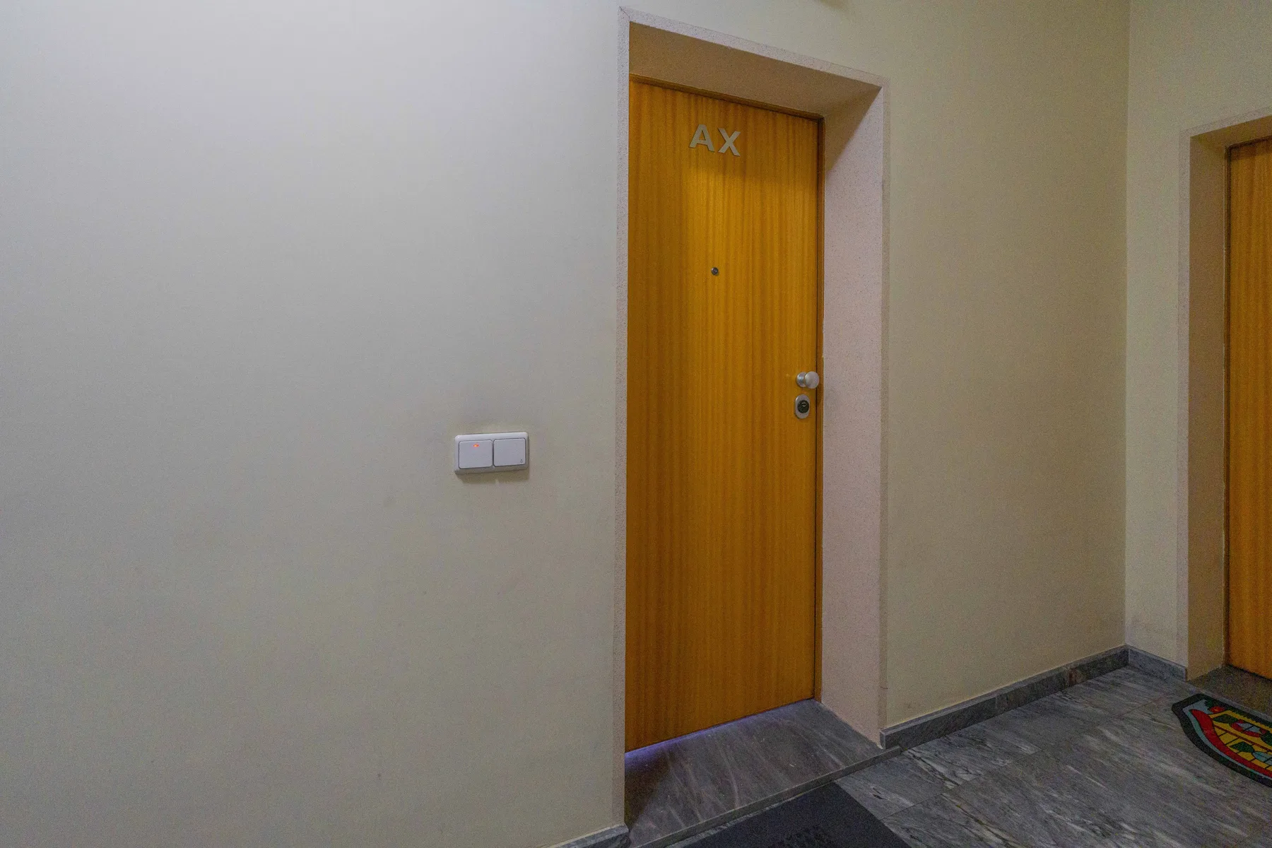 Un pasillo interior con una puerta de madera y otra entrada.