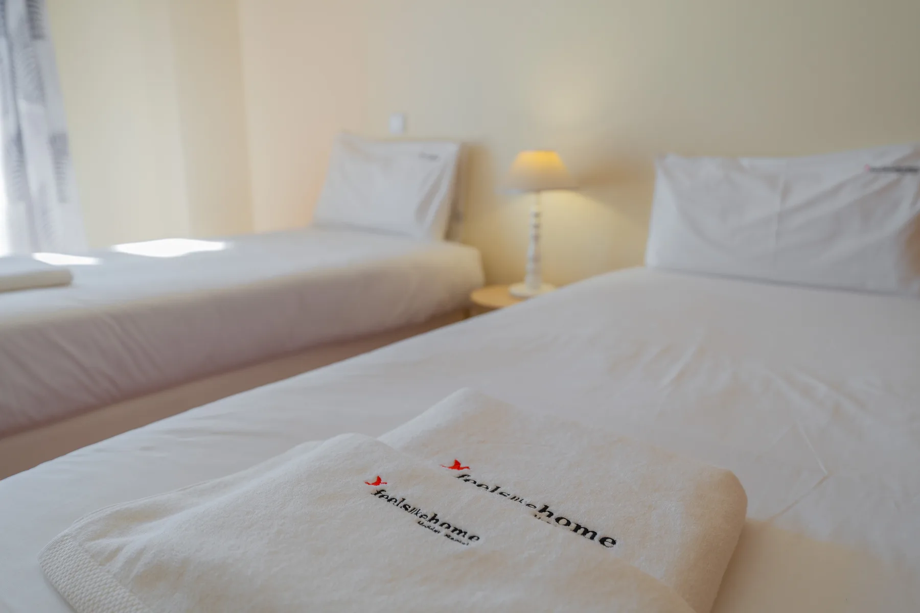 Un dormitorio con camas, toallas dobladas y una lámpara de mesita.