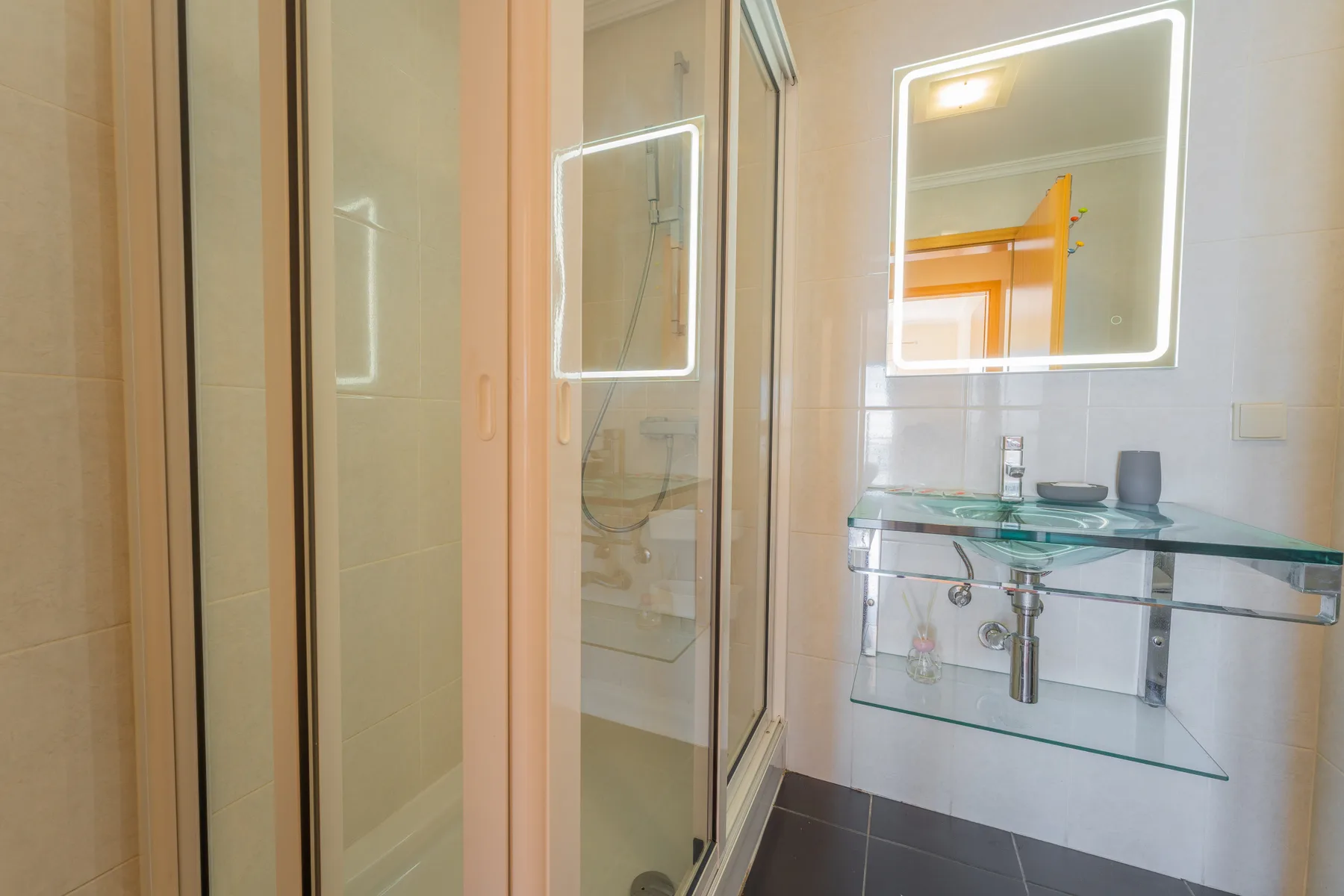 Un baño con una ducha de vidrio y un espejo de pared sobre el lavabo.