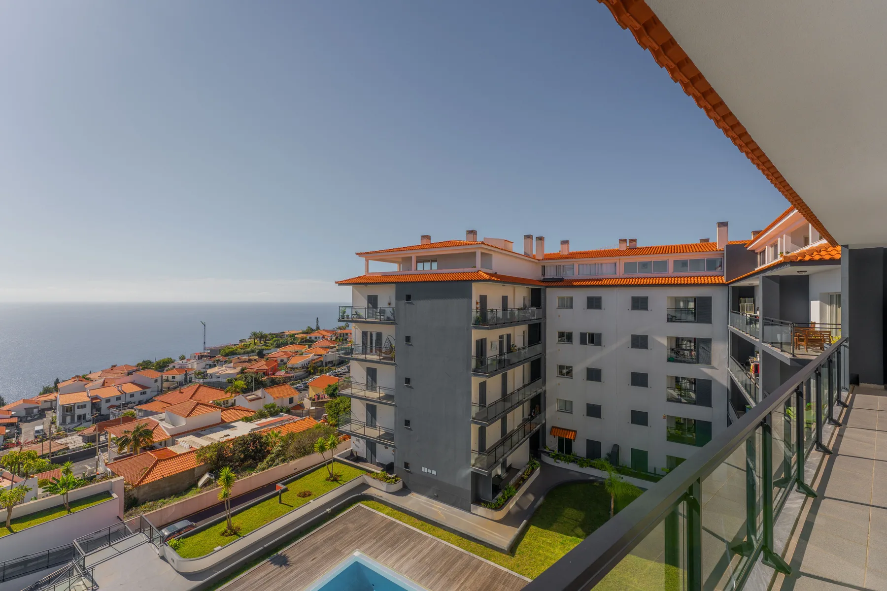 Edificios y tejados de apartamentos miran al océano desde un balcón.