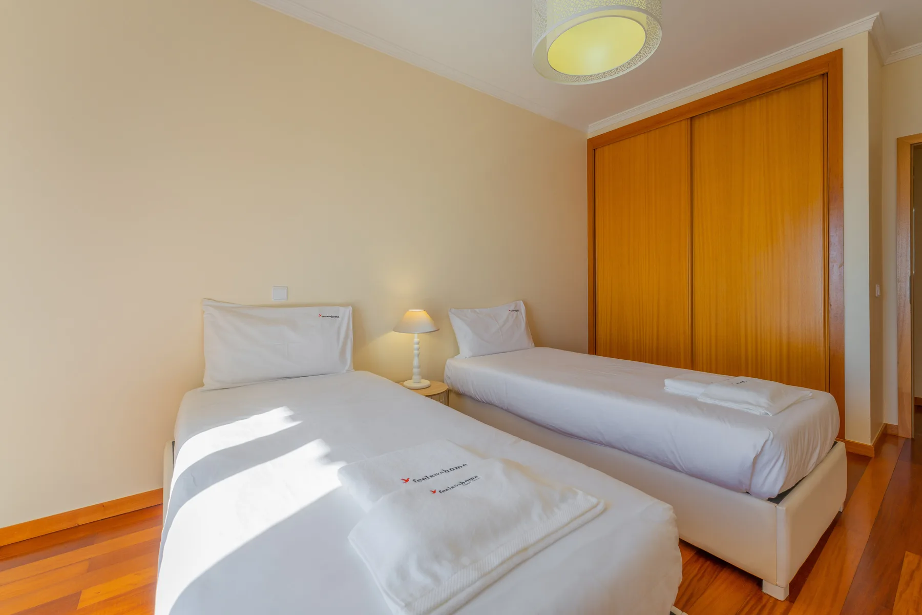 Dormitorio con dos camas, una lámpara de mesita y un armario de madera.