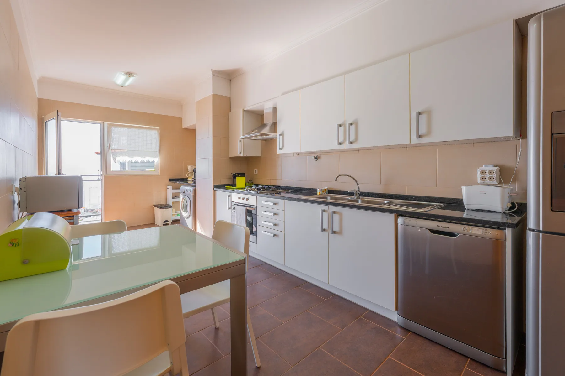 Una cocina luminosa con armarios blancos, una encimera y una mesa de comedor.