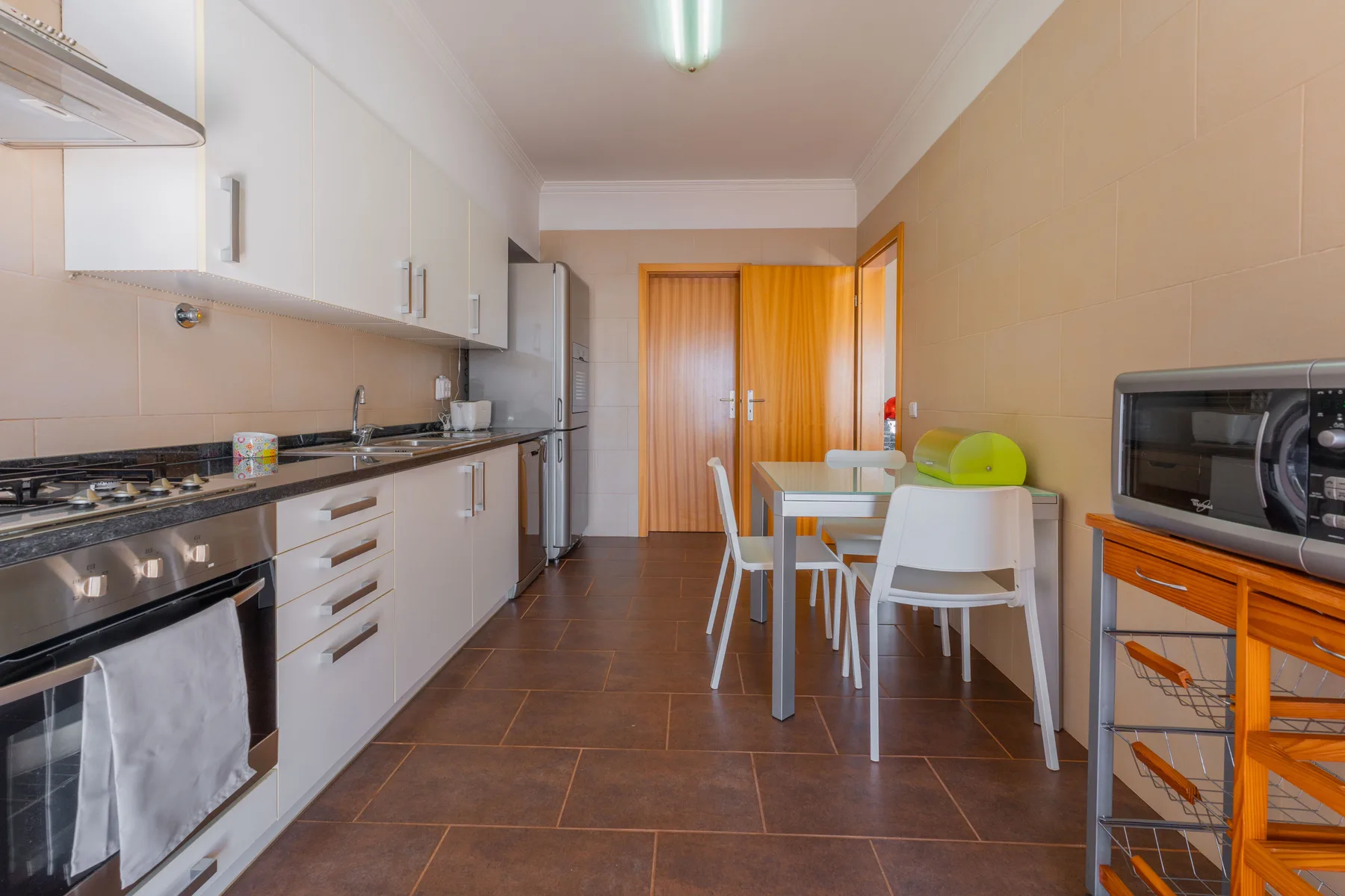Cocina y comedor con armarios blancos y una mesa.