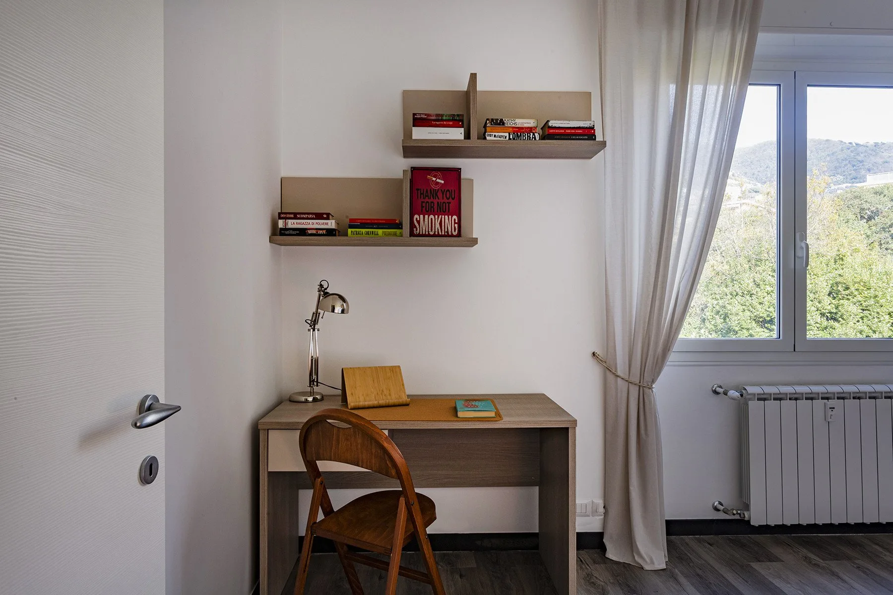 Un escritorio y una silla están junto a una ventana en una zona de estudio.