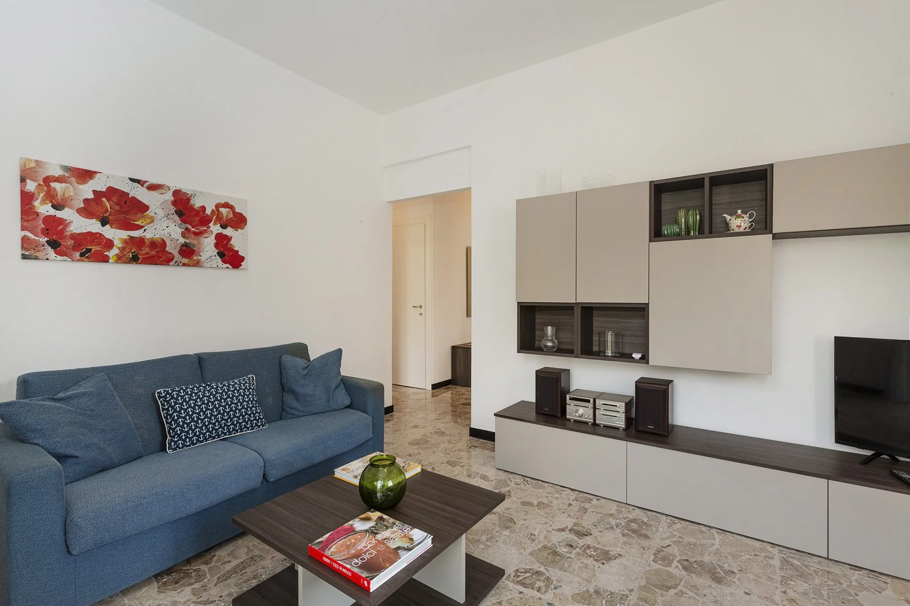 Una sala de estar con asientos azules, una mesa de centro y un mueble de entretenimiento.
