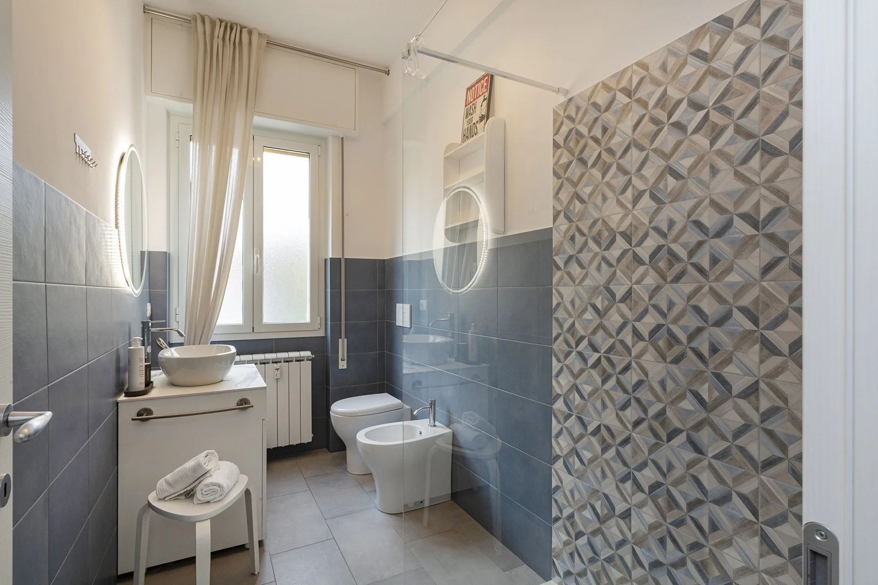 Un baño con lavabo, inodoro y azulejos estampados en la pared.
