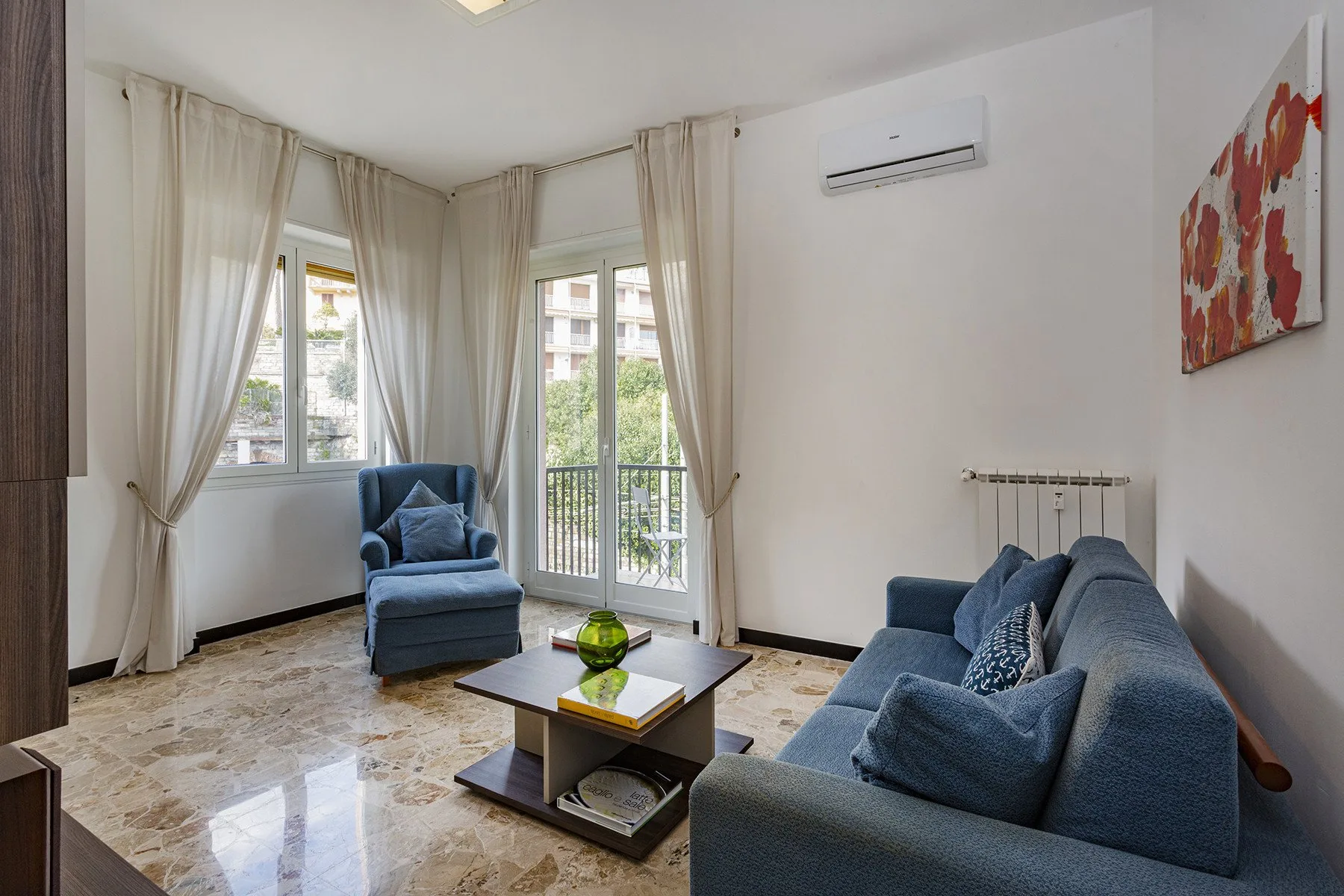 Una sala luminosa con asientos azules, una mesa de centro y ventanas altas.