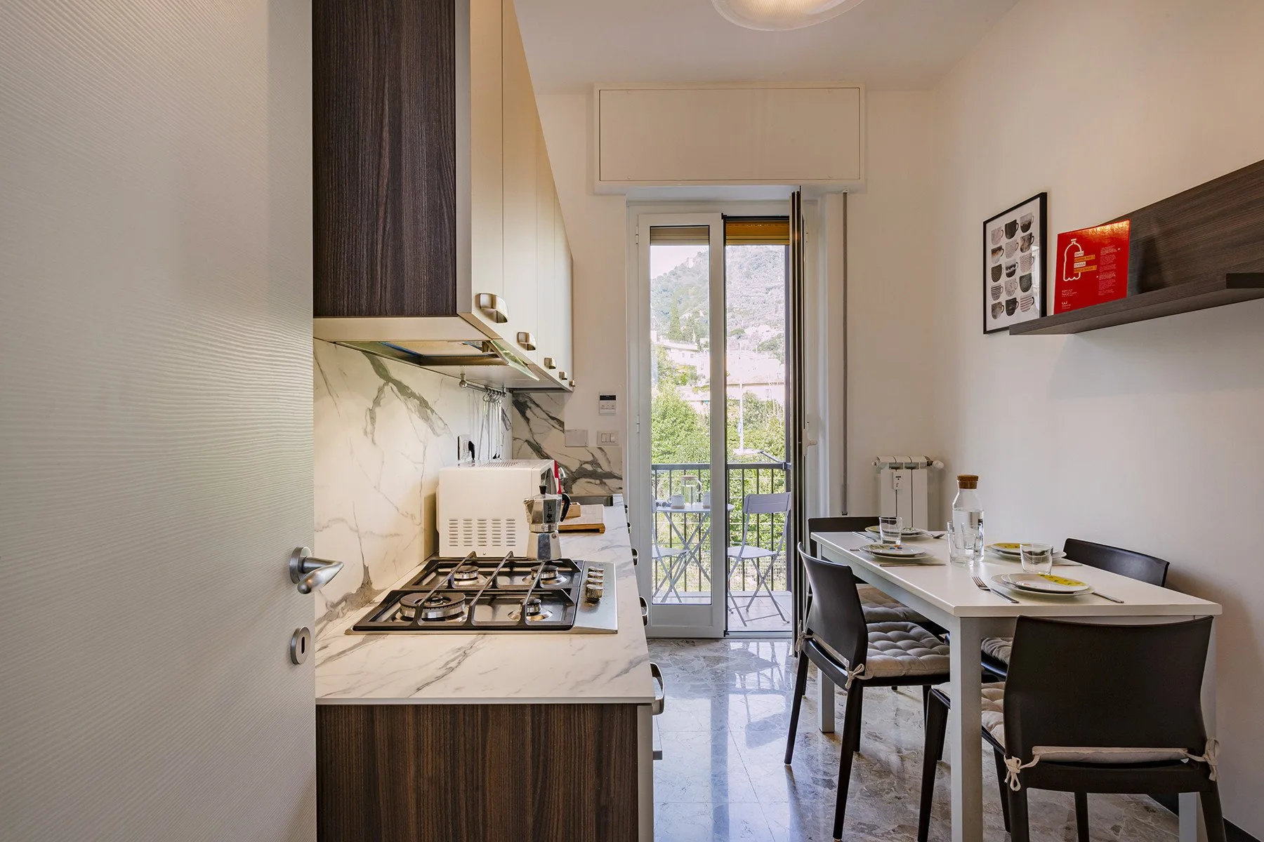 Una luminosa cocina con comedor se abre a un balcón mediante puertas de vidrio.
