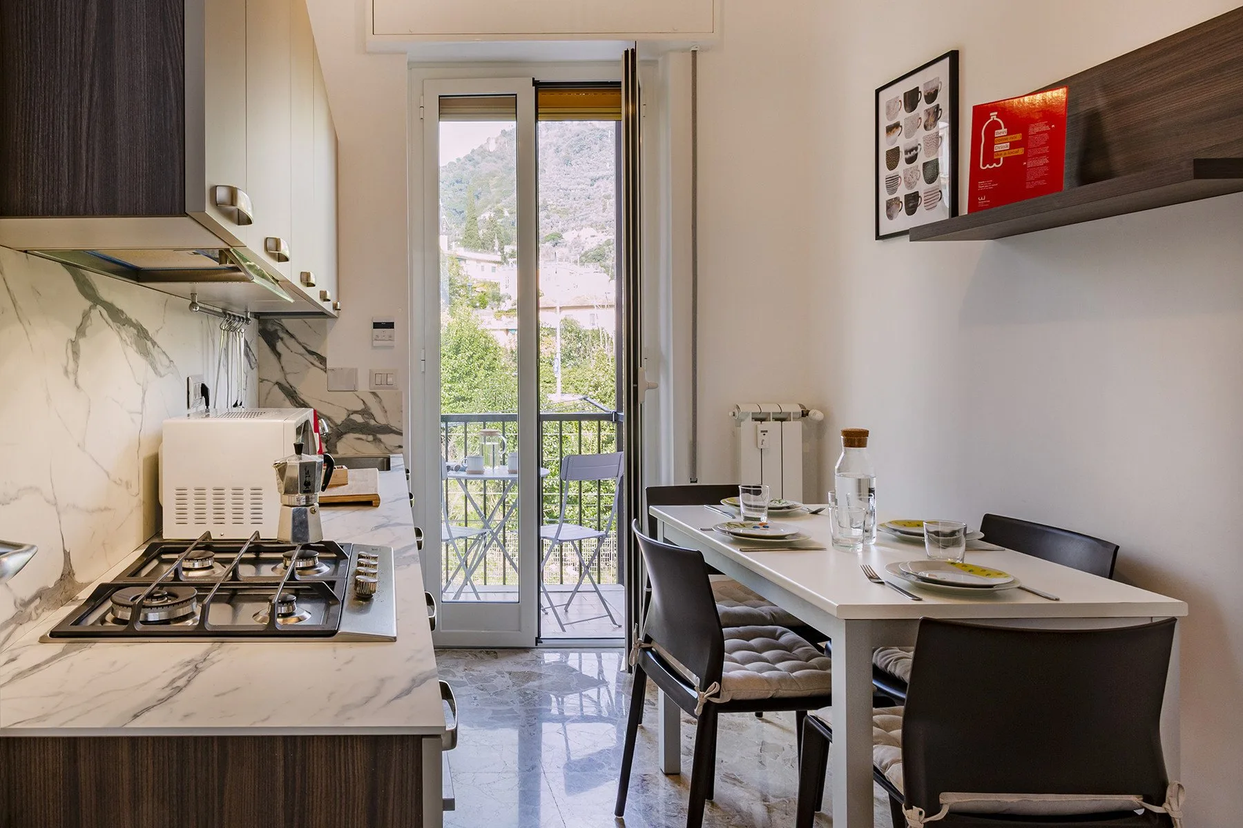 Una cocina compacta y comedor dan a un balcón con asientos al aire libre.