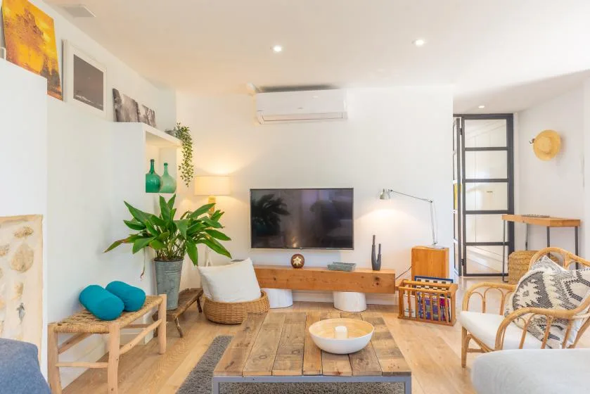 Una sala luminosa con un televisor sobre un mueble de madera.
