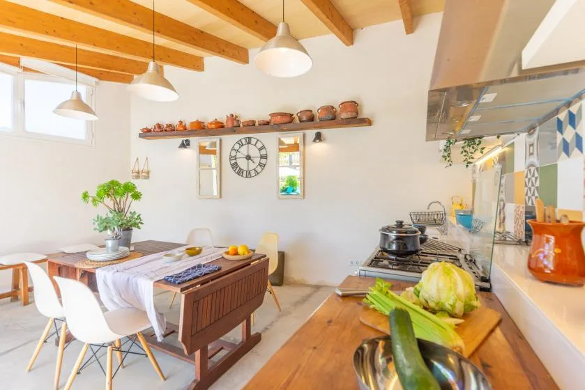 Una cocina y comedor luminosos con una mesa de madera y una encimera.