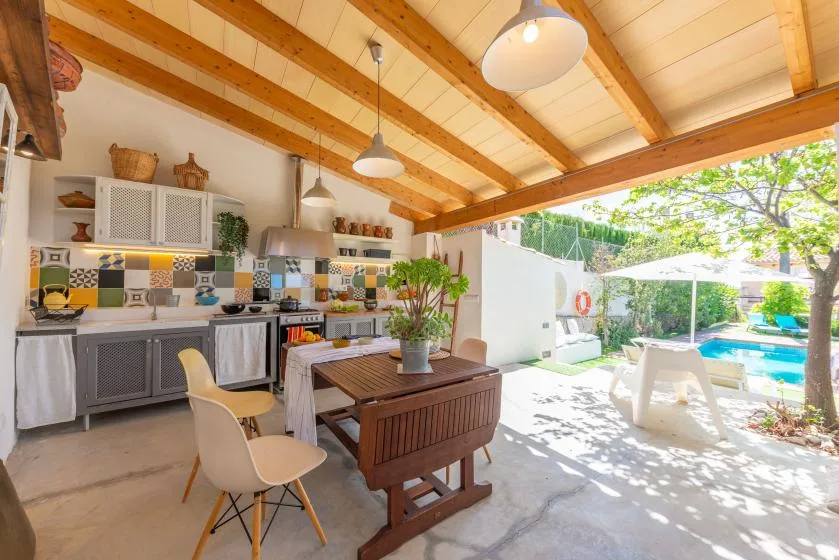 Una cocina abierta y zona de comedor dan a un patio soleado y una piscina.