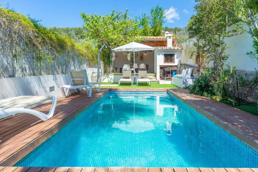 Una piscina al aire libre con asientos junto a un patio sombreado.