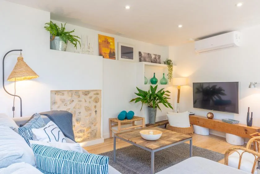 Una sala luminosa con asientos, una mesa de centro y un televisor.