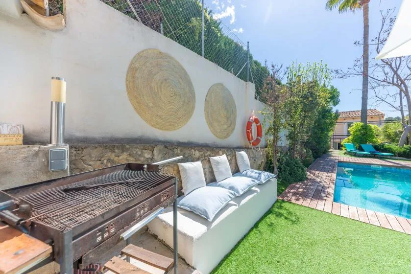 Un patio al aire libre con asientos acolchados junto a una piscina.
