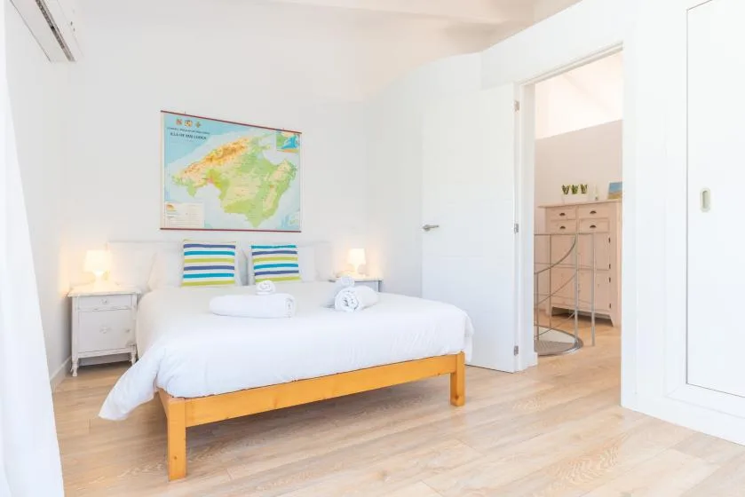Un dormitorio luminoso con una cama bien tendida y un mapa colorido en la pared.