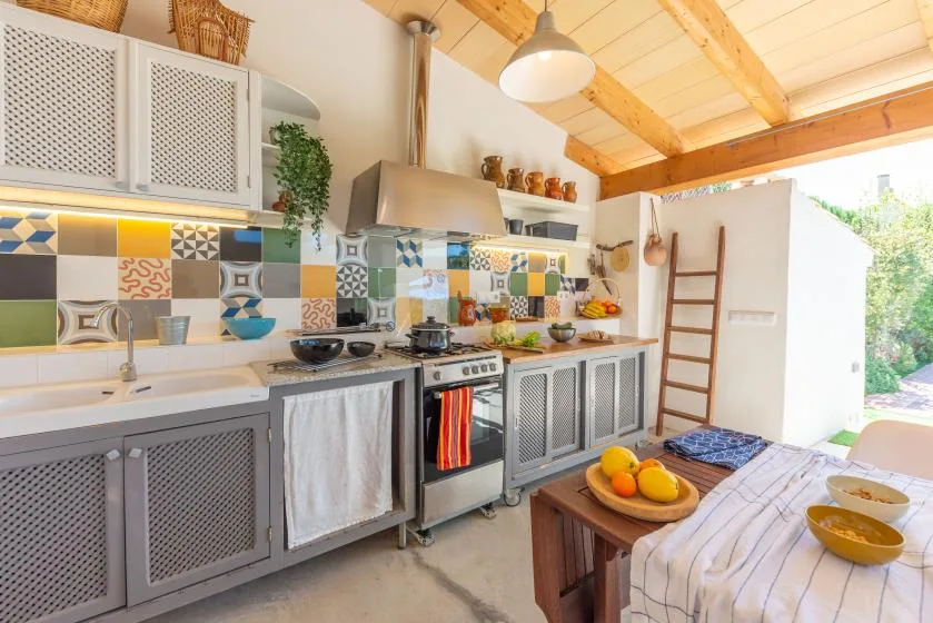 Una cocina luminosa con azulejos estampados de colores y una mesa de comedor en primer plano.