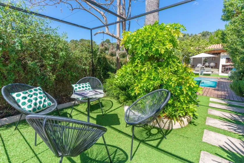 Una zona de estar al aire libre junto a un sendero de jardín, con una piscina al fondo.