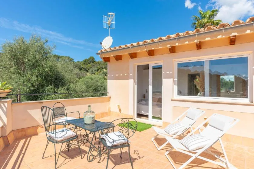 Una terraza soleada con asientos y tumbonas junto a una casa.
