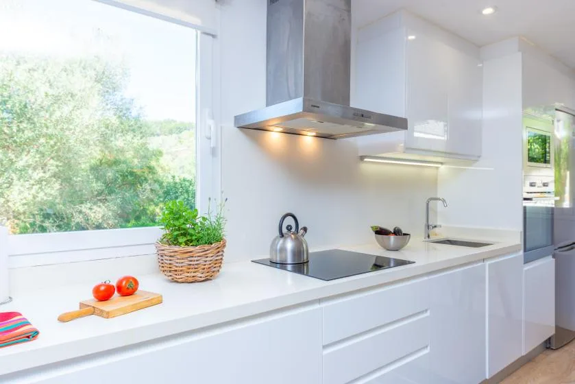 Una cocina moderna y luminosa con gabinetes blancos, una estufa y una ventana grande.