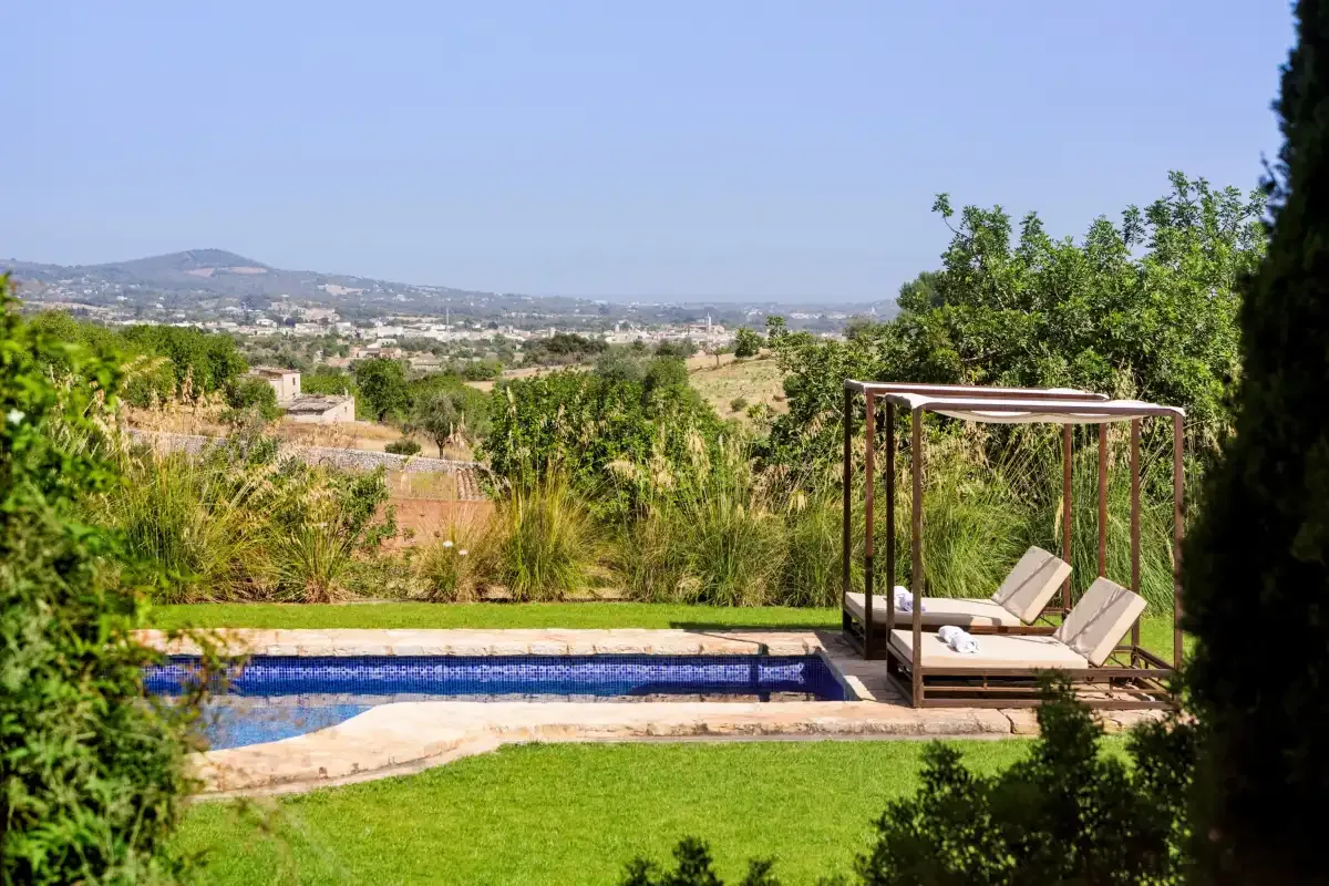 A swimming pool and lawn overlook a green rural landscape.