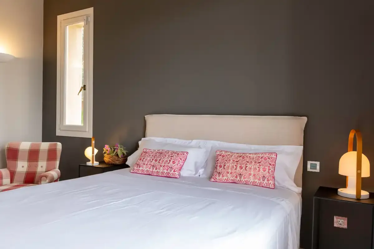 A bedroom with a large bed and patterned cushions.