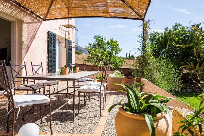 An outdoor patio with a dining table and seating beneath a woven canopy.