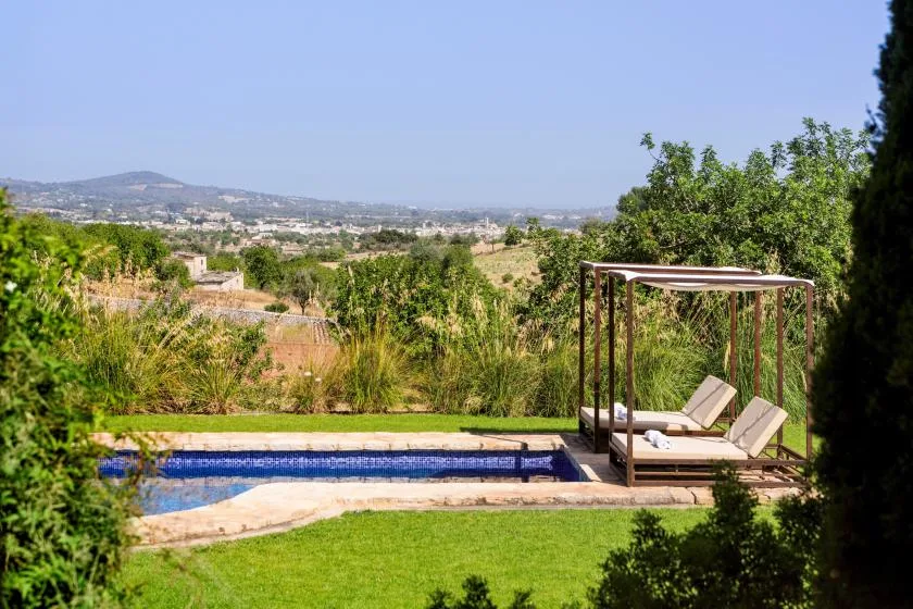 An outdoor pool and lawn overlook a green valley and distant hills.