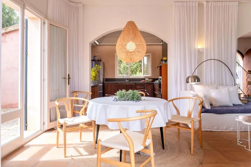 A bright dining area with a round table and an adjoining kitchen.