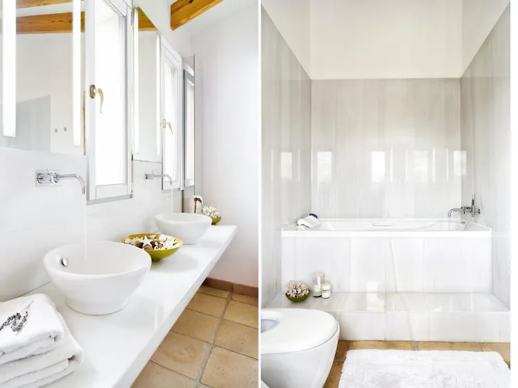 A bright bathroom with a long vanity, sinks, and a bathtub.