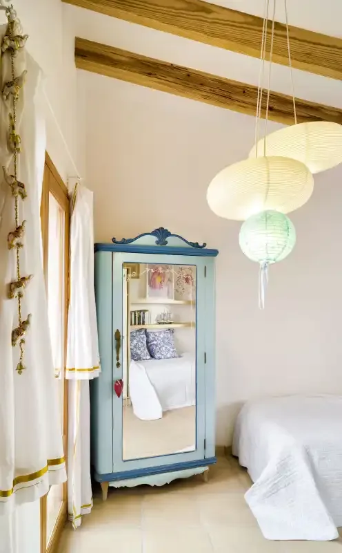 A bright bedroom with a blue mirrored wardrobe and hanging pendant lights.