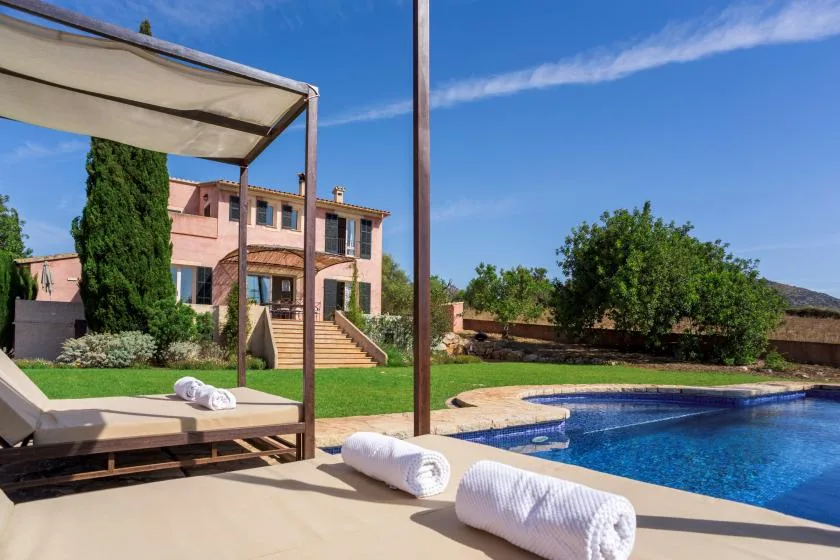 A swimming pool beside a landscaped patio and a two-story building.