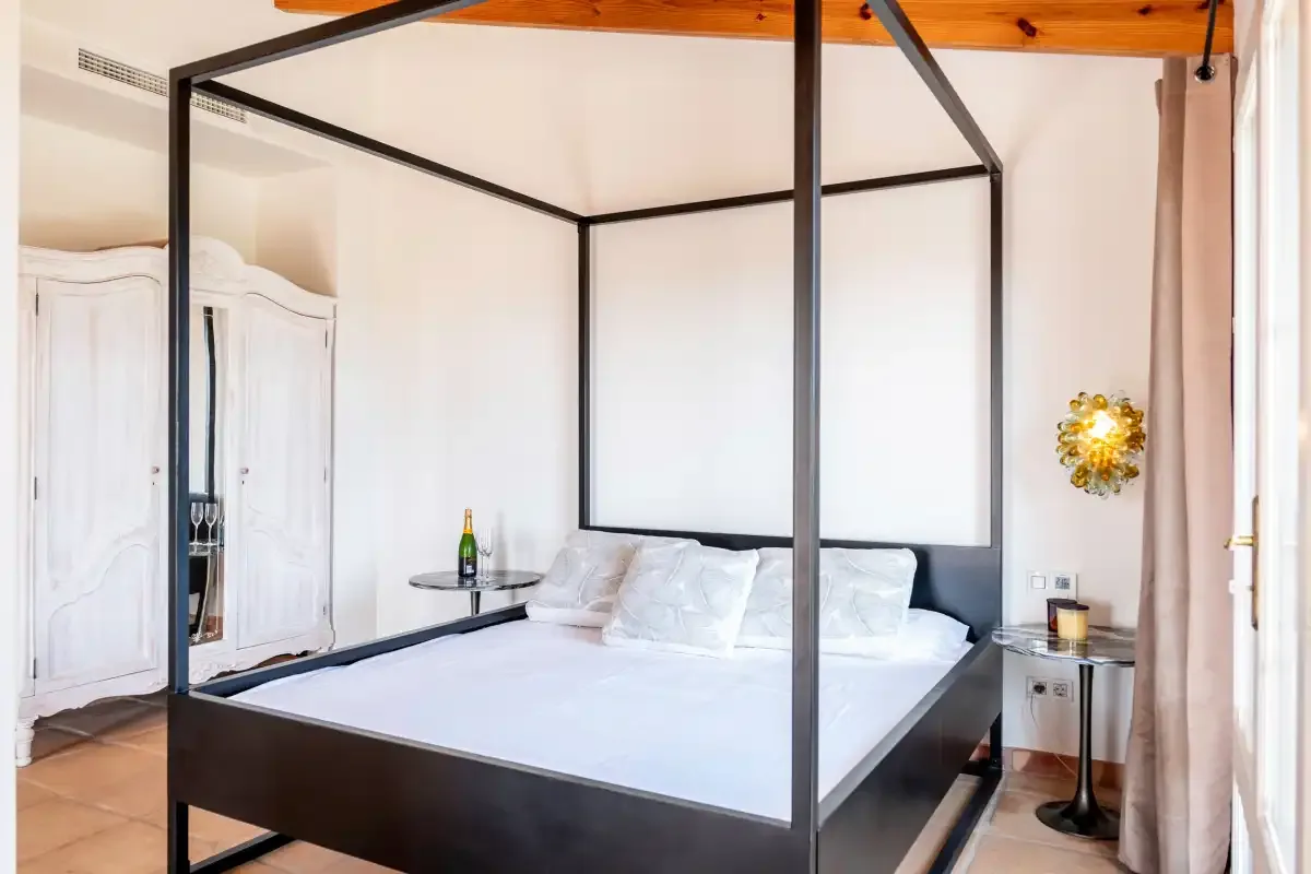 A bedroom with a large bed, white bedding, and bedside tables.