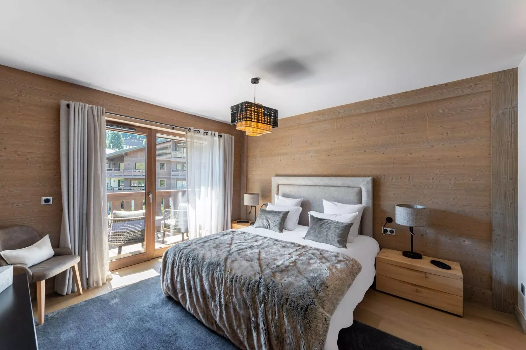 A bedroom with a bed beside a glass door opening onto a balcony.