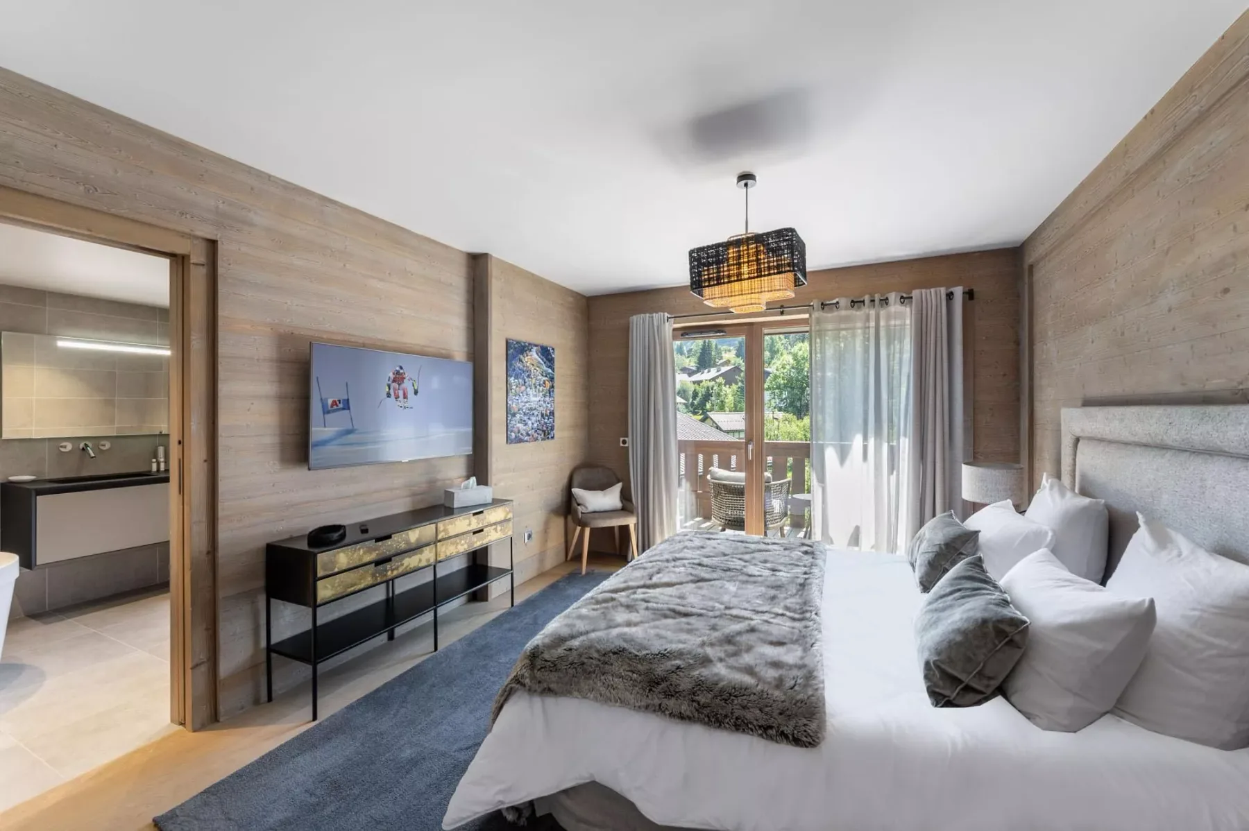 A bedroom with a large bed, wall-mounted television, and glass doors opening to a balcony.