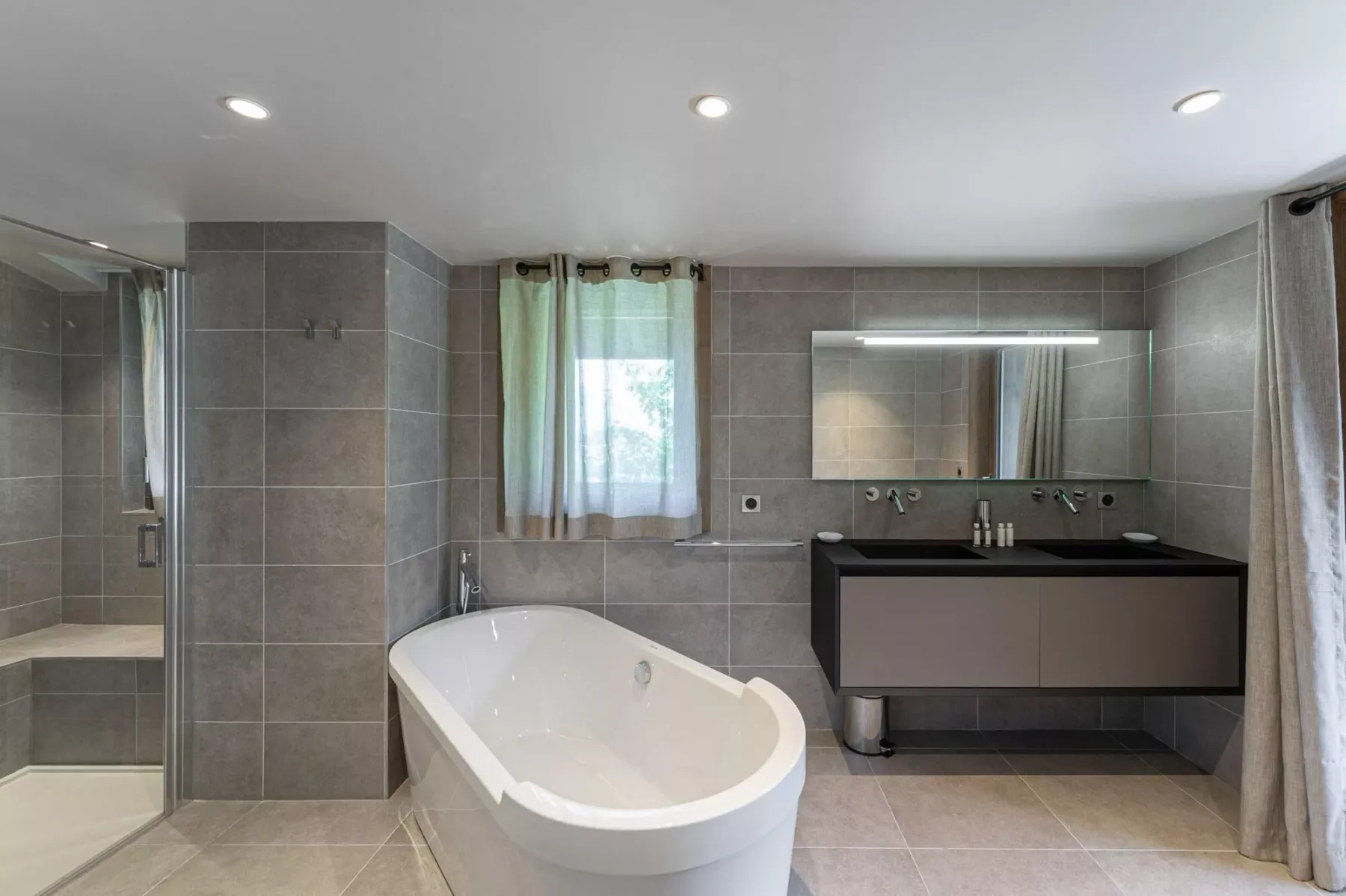 A tiled bathroom with a bathtub, glass shower, and vanity.