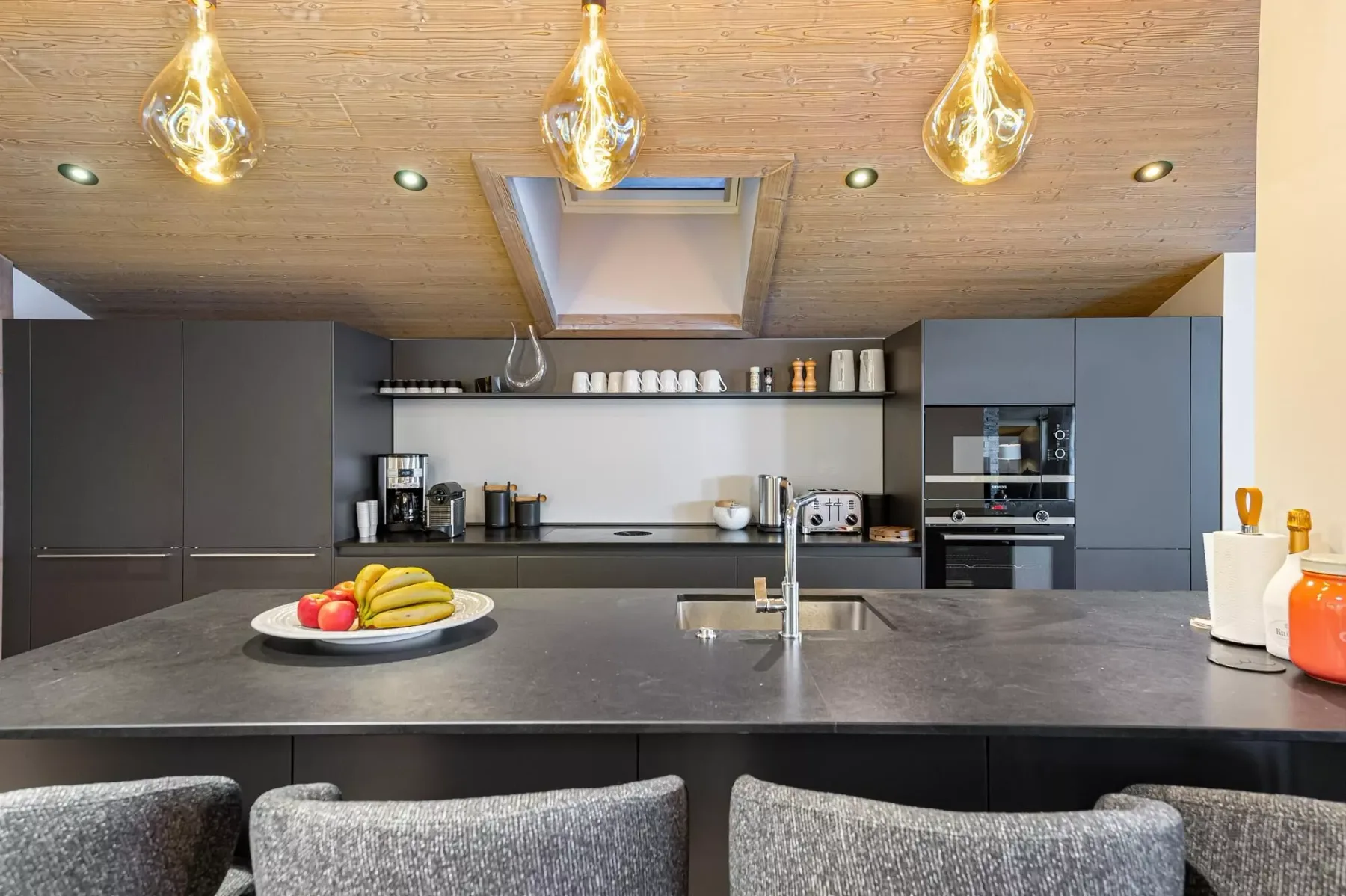 Una cocina moderna con una amplia isla y luces colgantes.