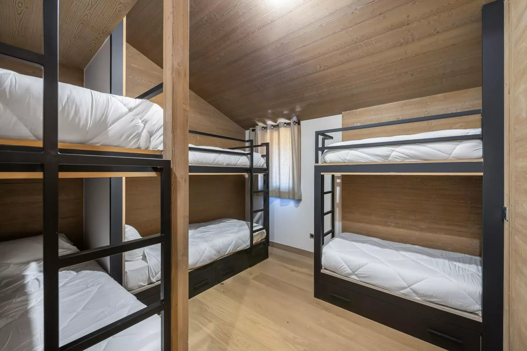 A wood-paneled bedroom with several bunk beds and white bedding.
