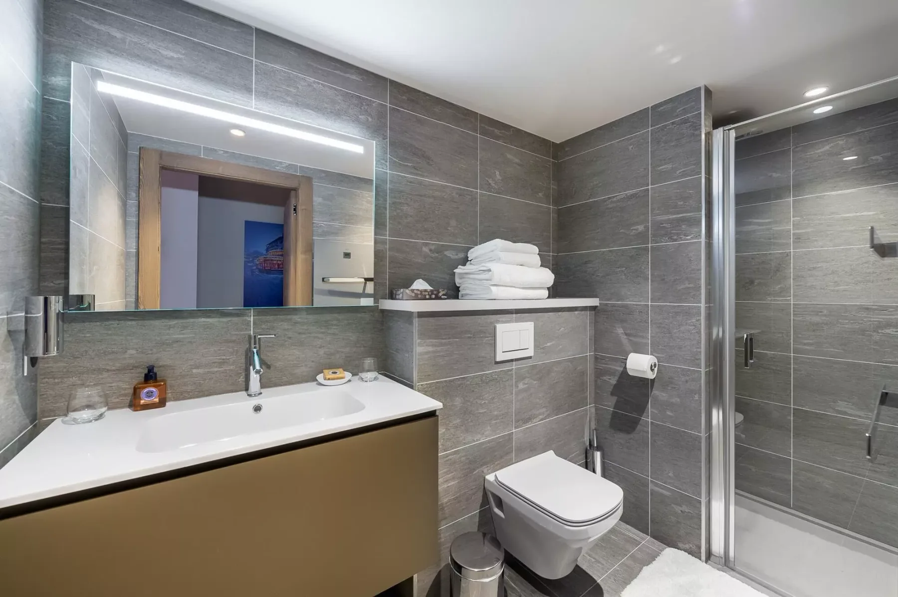 A modern bathroom with a sink, toilet, and glass-enclosed shower.