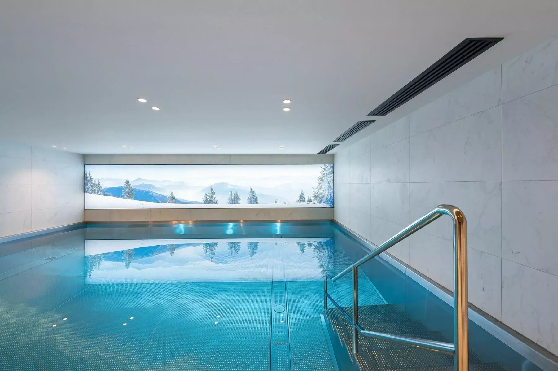An indoor swimming pool with a wide window overlooking a snowy landscape.