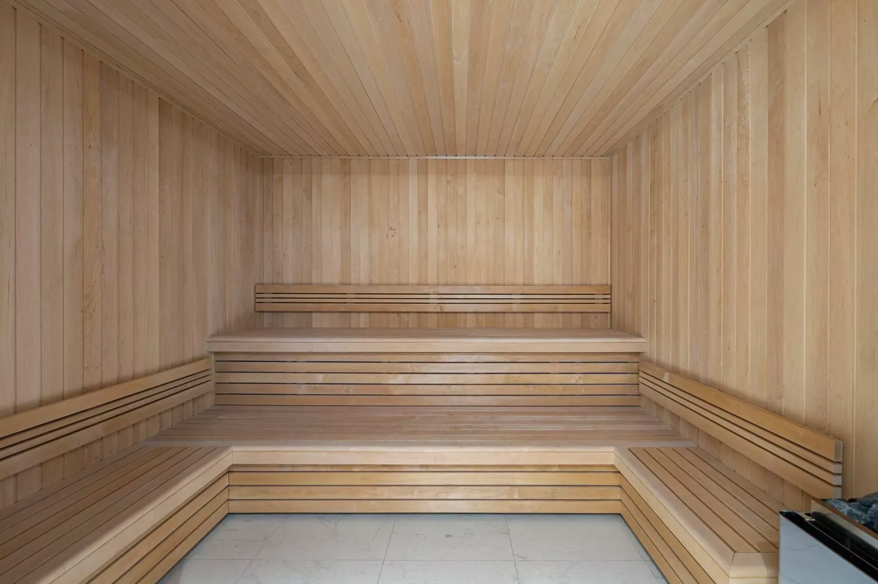 A wood-paneled sauna room with tiered benches and a tiled floor.