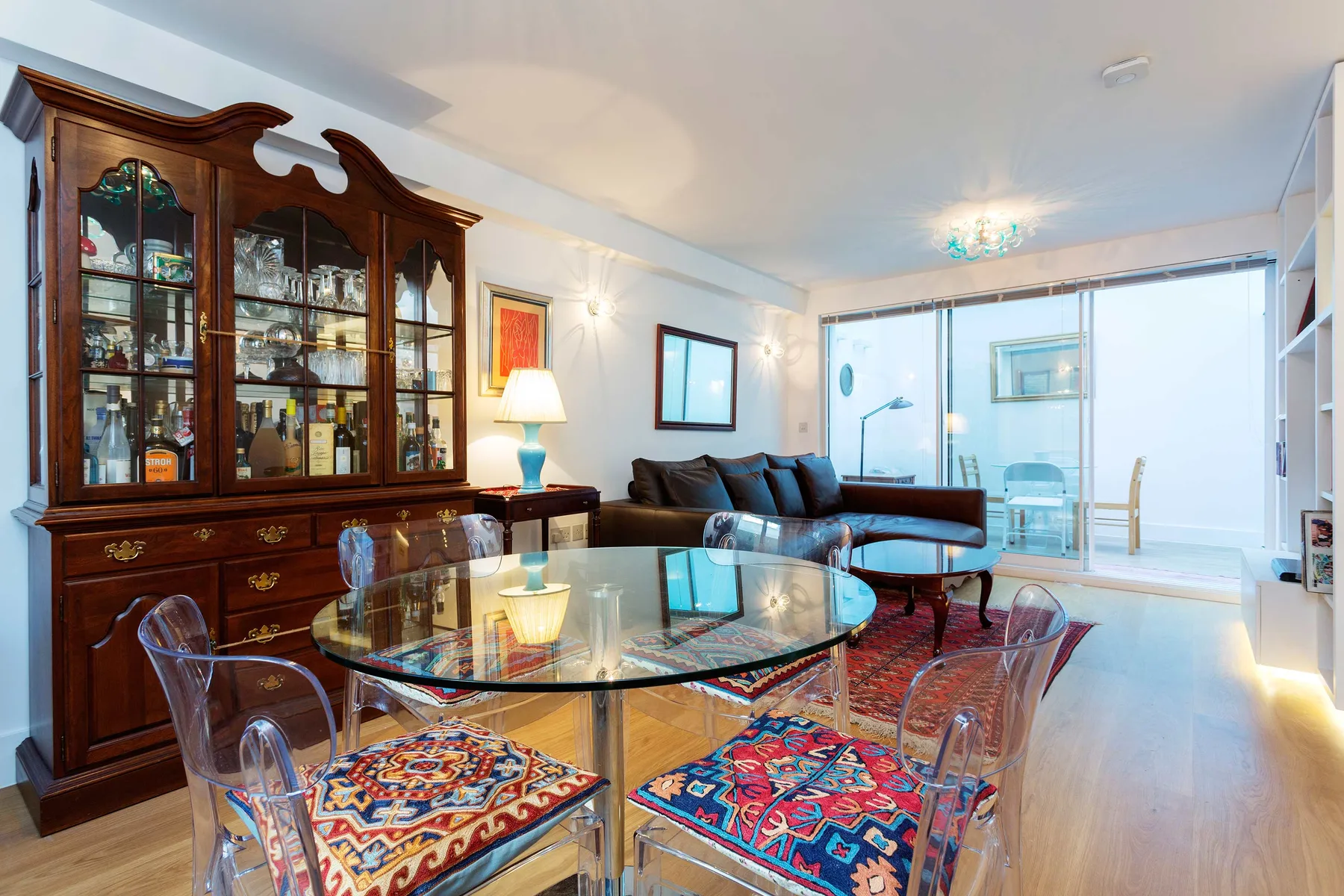 Una sala de estar y comedor con una mesa de vidrio y un mueble de madera oscura.